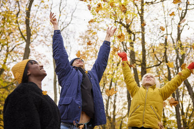 Happy young friends throwing autumn leaves