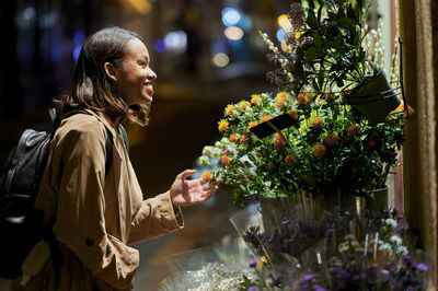 Happy young woman touching flower at night