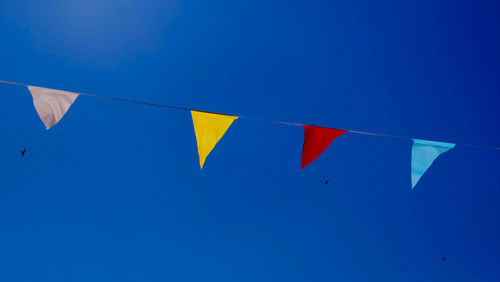 Low angle view of flag against clear blue sky