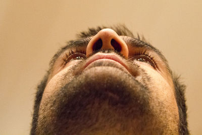 Close-up of man looking up against brown background