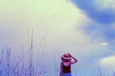 Rear view of woman standing against cloudy sky