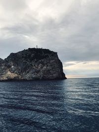 Rock formation in sea against sky