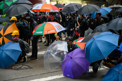 People on wet umbrella in city