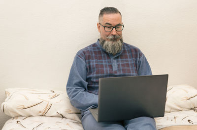 Senior man using laptop while sitting on sofa at home