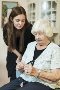 Granddaughter looking at grandmother fixing necklace