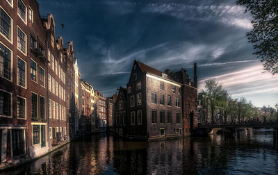 Canal amidst buildings in city against sky at dusk