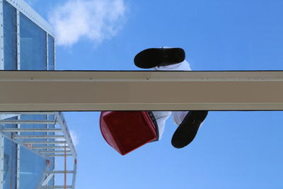 Directly below view of cleaner on skylight against blue sky