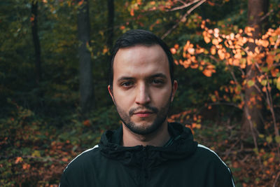 Portrait of young man with autumn leaves in forest