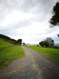 Road amidst field against sky