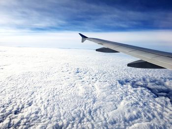 Airplane flying over snowcapped mountain against sky