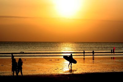 Silhouette people standing on beach against sky during sunset