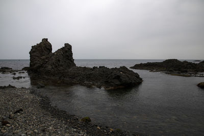Rock formations on beach against sky