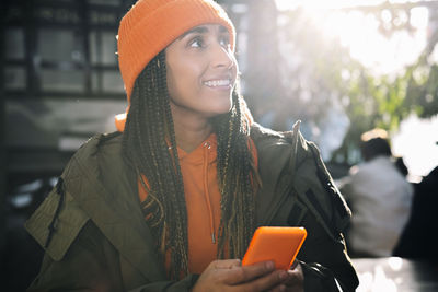 Contemplative woman with smart phone on sunny day