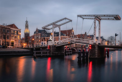 Bridge over river against sky in city
