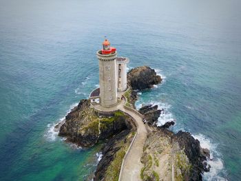 Lighthouse by sea against sky