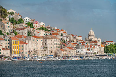 Buildings by sea against sky