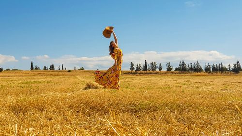 Side view of woman standing on field against sky