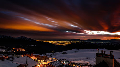 Illuminated cityscape against sky during sunset
