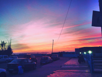 Cars on city against sky during sunset