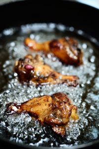 Close-up of chicken wings frying in cast iron skillet