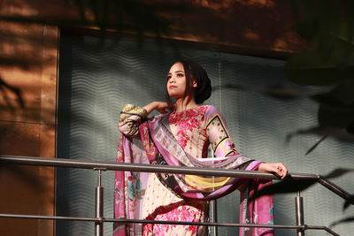 Young woman looking away while standing on railing