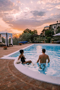 Rear view of couple in swimming pool against sky