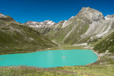 Scenic view of lake and mountains against blue sky