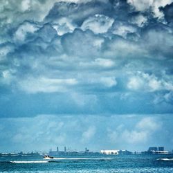 Boat sailing in sea against cloudy sky