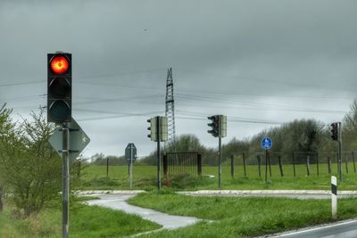 Low angle view of railway signal and electricity pylon on field 