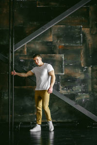 Portrait of muscular man standing by wall