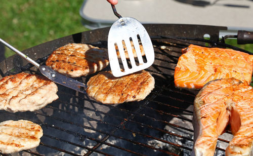 High angle view of meat and salmon steaks on barbecue grill