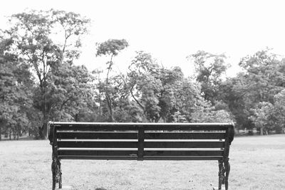 Bench against trees against clear sky