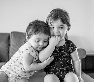 Cute sisters sitting on sofa at home