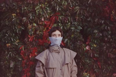 Portrait of young man standing against plants