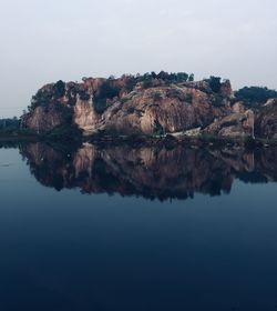 Scenic view of lake by cliff against sky