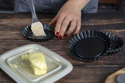 Women preparing delicious blue berry tart or pie .spread butter on small tart plates.