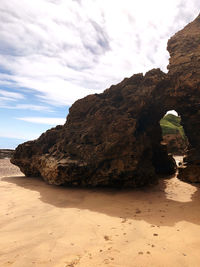 Rock formation on beach against sky