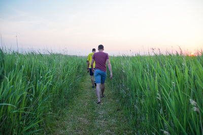 Rear view of men walking on field