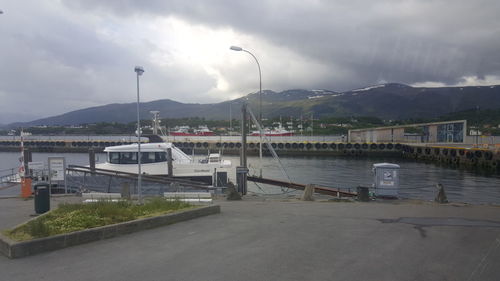 Boats at harbor against cloudy sky