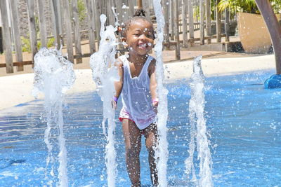 Happy girl playing with fountain at water park