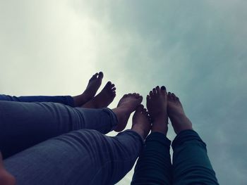 Low section of women with feet up against sky