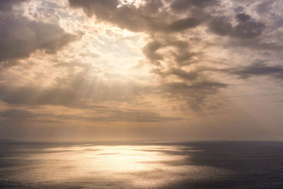 Sun shining through clouds onto the sea