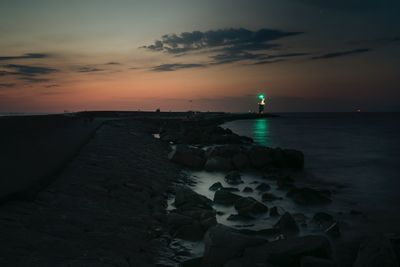 View of illuminated lighthouse against sky during sunset