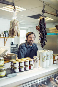 Portrait of confident mature salesman at supermarket counter