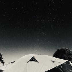 Low angle view of silhouette trees and tent against sky at night