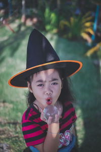 Portrait of girl wearing witch hat holding crystal ball