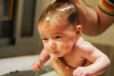 Cropped hands bathing cute baby girl in bathroom