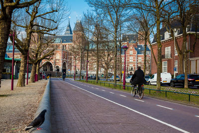 People riding bicycle on street amidst buildings in city