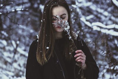 Portrait of young woman holding ice cream cone during winter
