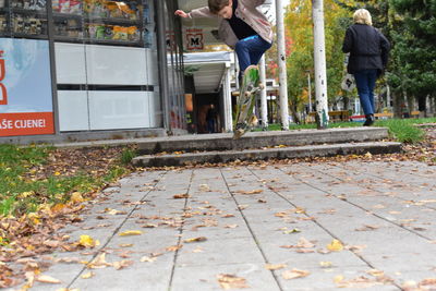 Low section of people standing on footpath during autumn